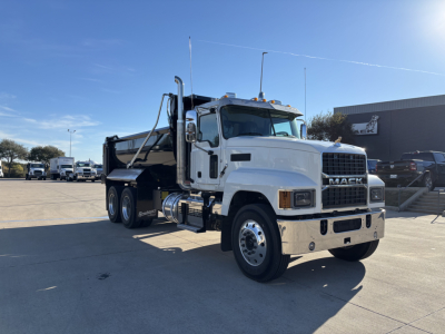 Mack PI64 dump truck in white and black, side view showing dump body and dual rear axles, chrome bumper, Mack grille, blue sky.