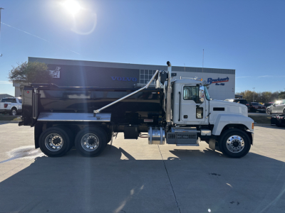 Mack PI64 dump truck side view showing black dump body, white cab, triple rear axles, hydraulic raise trailer mechanism and metal steps.