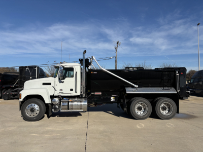 Truck side view of a 2026 Mack PI64 dump truck showing a white cab, black dump body, and dual rear axles.