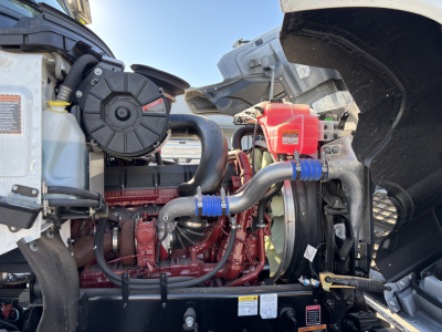 Mack PI64 engine bay showing red diesel engine with hoses, coolant reservoir, air intake, and radiator assembly.
