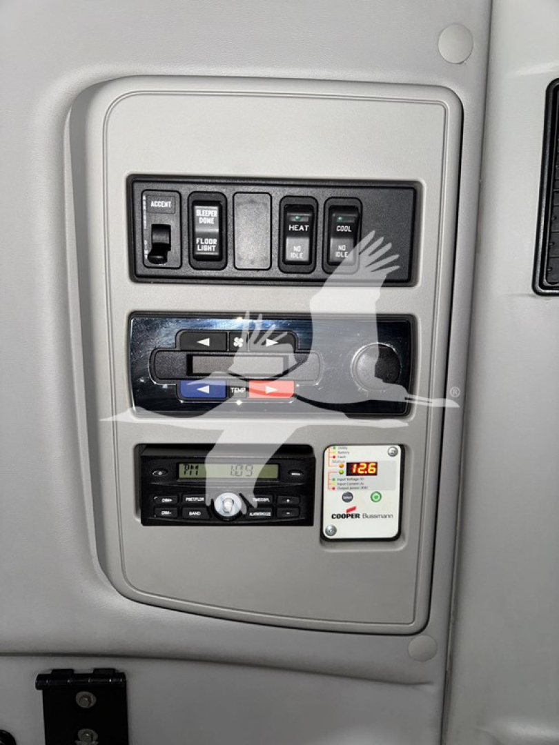 Dashboard control panel and auxiliary gauges in a sleeper truck cab, with climate/aux switches and a CO2/DEF-style display visible.