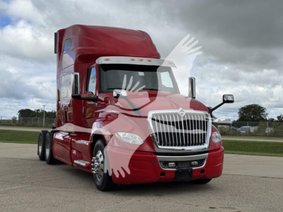 Truck front-left view showing red 2019 International LT sleeper cab with chrome grille and dual rear axles.