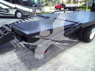 Flatbed truck deck and winch area showing diamond plate surface and hitch components on Freightliner M2 106 under clear outdoor light.