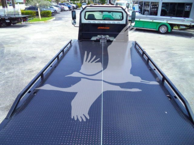 Flatbed truck bed of a 2012 Freightliner M2 106 showing a diamond plate surface with rails along the sides and the cabin with JERR-DY? branding visible.