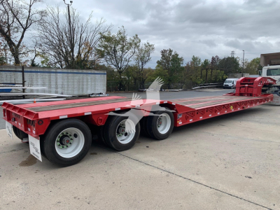 Lowboy trailer showing long red flatbed with triple axles and white wheels, part of a 2027 Eager Beaver 50Gsl-Pt.