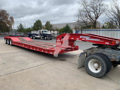 Lowboy trailer by Eager Beaver 50Gsl-Pt with red frame and long deck showing label 50GSL-PT on gooseneck and wheel area.