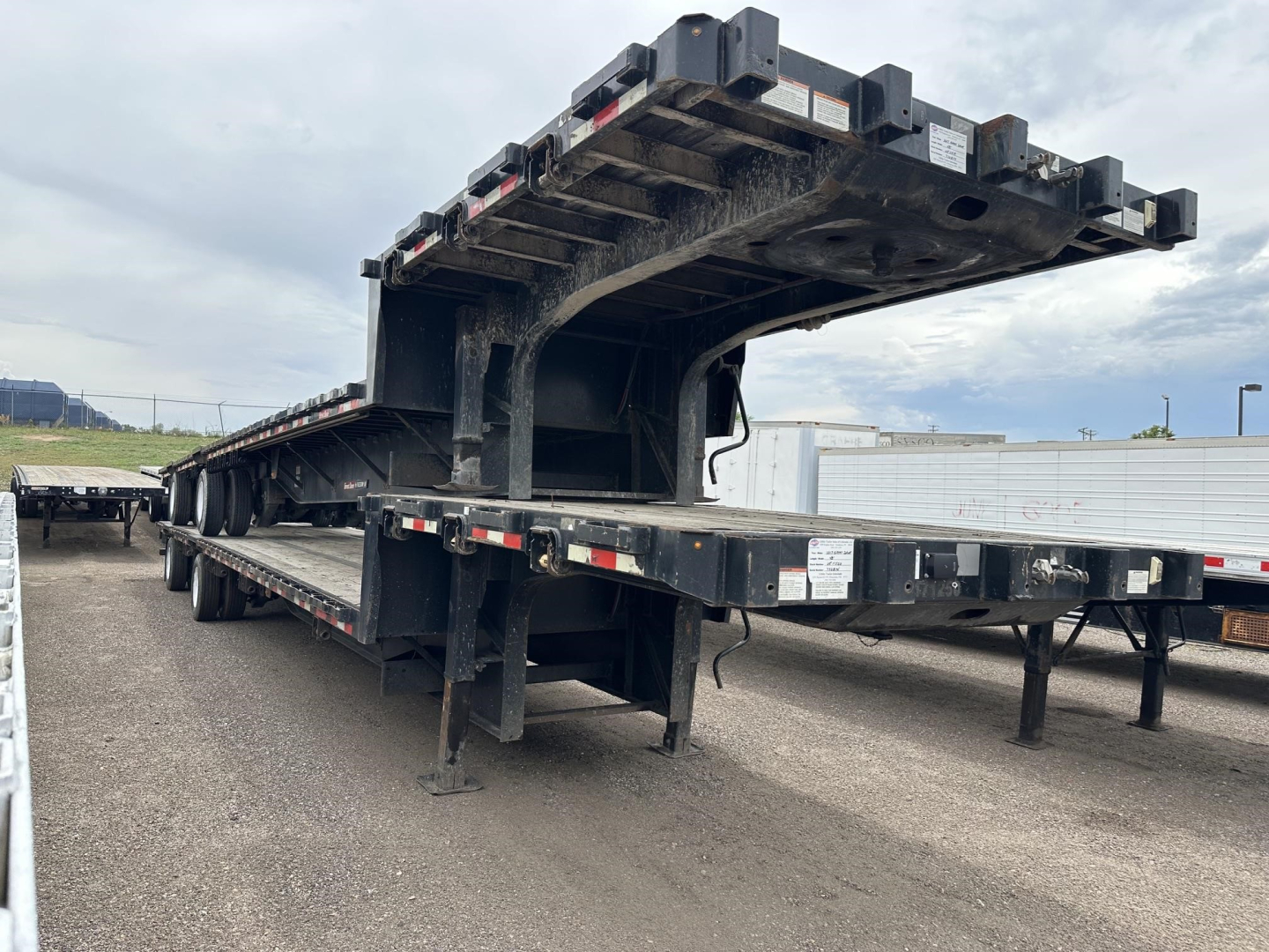 Heavy steel Great Dane drop deck trailer with air drop deck in view, side rails, and multiple axles in a used condition.