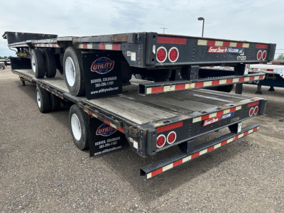 Flatbed drop deck trailer stacked on two levels with branding and reflective tape, Utility logo visible, Denver Colorado contact