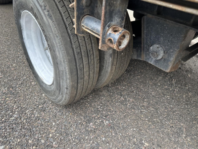 Dual rear wheels of a Great Dane trailer axle assembly with rusted hitch/connector and black undercarriage components.
