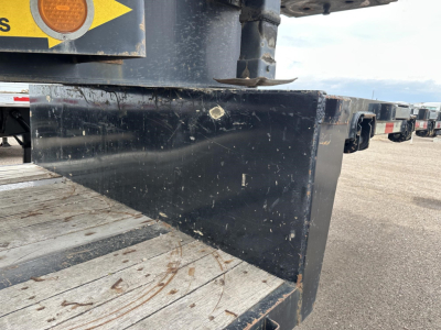 Steel spread air drop deck trailer side view showing black steel frame and wooden deck, with scratches and dirt.