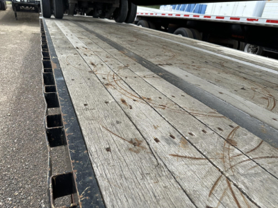 Great Dane steel spread air drop deck trailer bed showing wooden planks with metal side rail and pins.