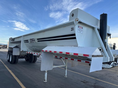 Load King RH32-29 dump trailer side view showing tandem axle, white body with black stripe decals, raised gooseneck, landing gear, and safety decals.