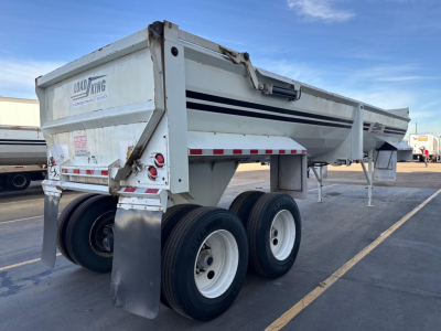 Load King dump trailer RH32-29 with dual rear axles parked outdoors, white with black stripes, VIN 150118276621 visible near front left, stock UE11339.