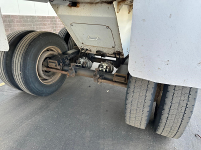 Trailer underside showing axles and dual wheels of a 2021 Load King RH32-29 dump trailer, with suspension axle components and tire tread visible.