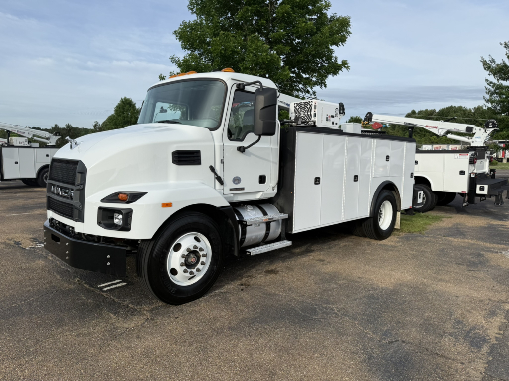 Mack MD6 service truck in view showing side compartments and utility body.
