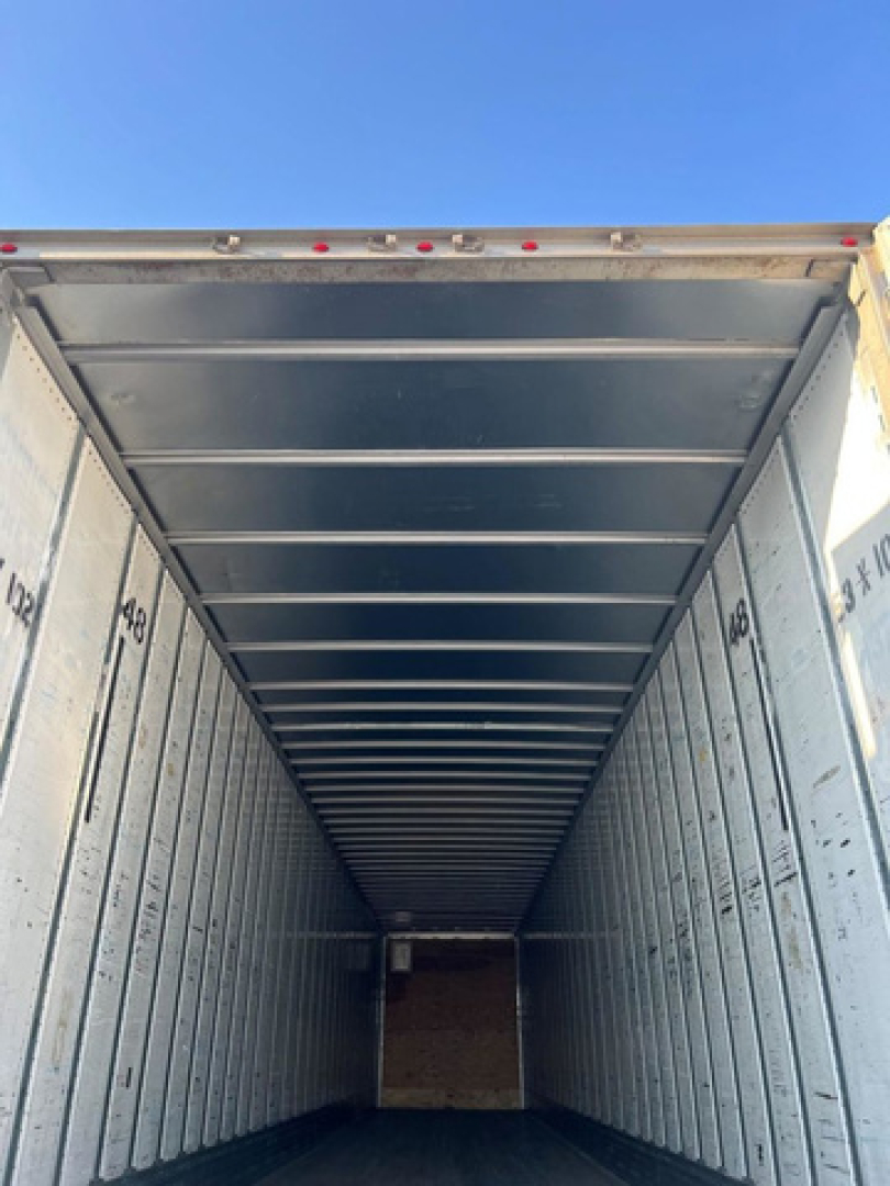 Inside trailer van cargo area showing metal walls and ceiling with side markings.