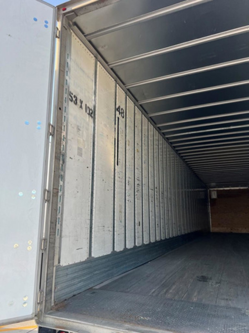 Interior of a utility van trailer showing aluminum side walls and ribbed ceiling, empty cargo area.