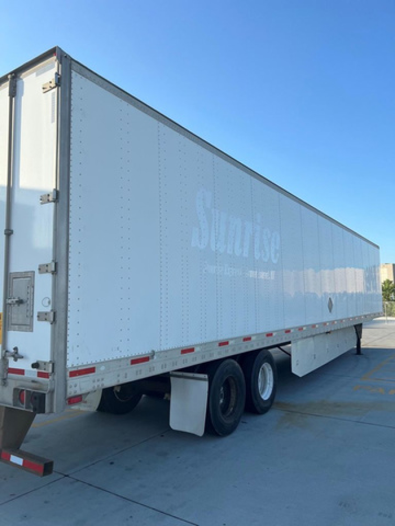 Utility van trailer side view showing Sunose logo and tandem axle with white riveted metal walls.