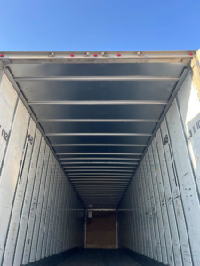 Inside trailer van cargo area showing metal walls and ceiling with side markings.