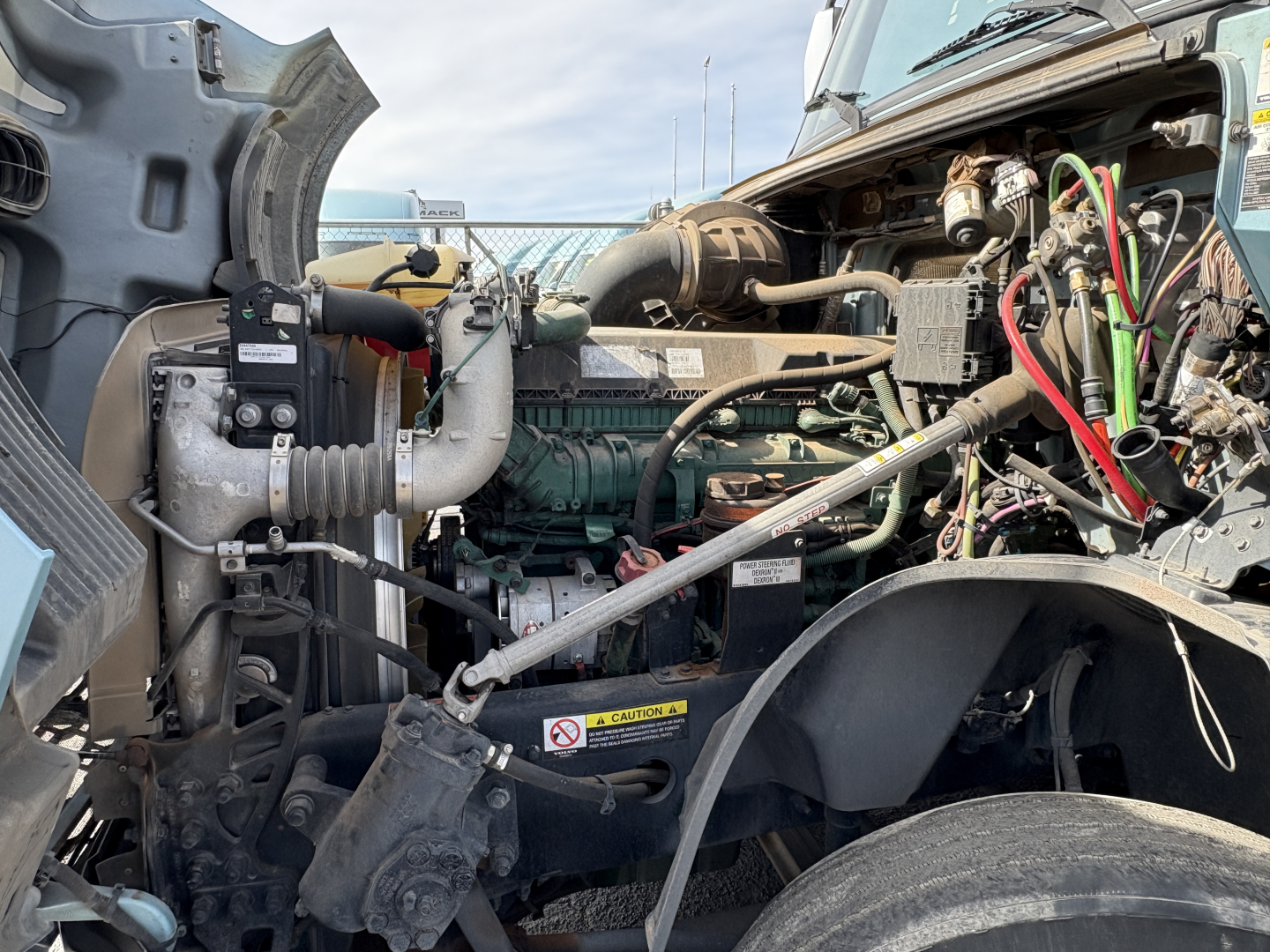 Volvo VNL64T760 engine bay showing cooling fan, hoses, wiring, and diesel engine components visible under open hood.