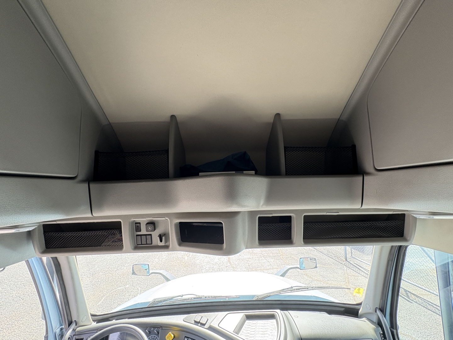 Cab interior overhead with storage compartments and dash area in Volvo VNL64T760 sleeper cab showing overhead compartments and cockpit window view.