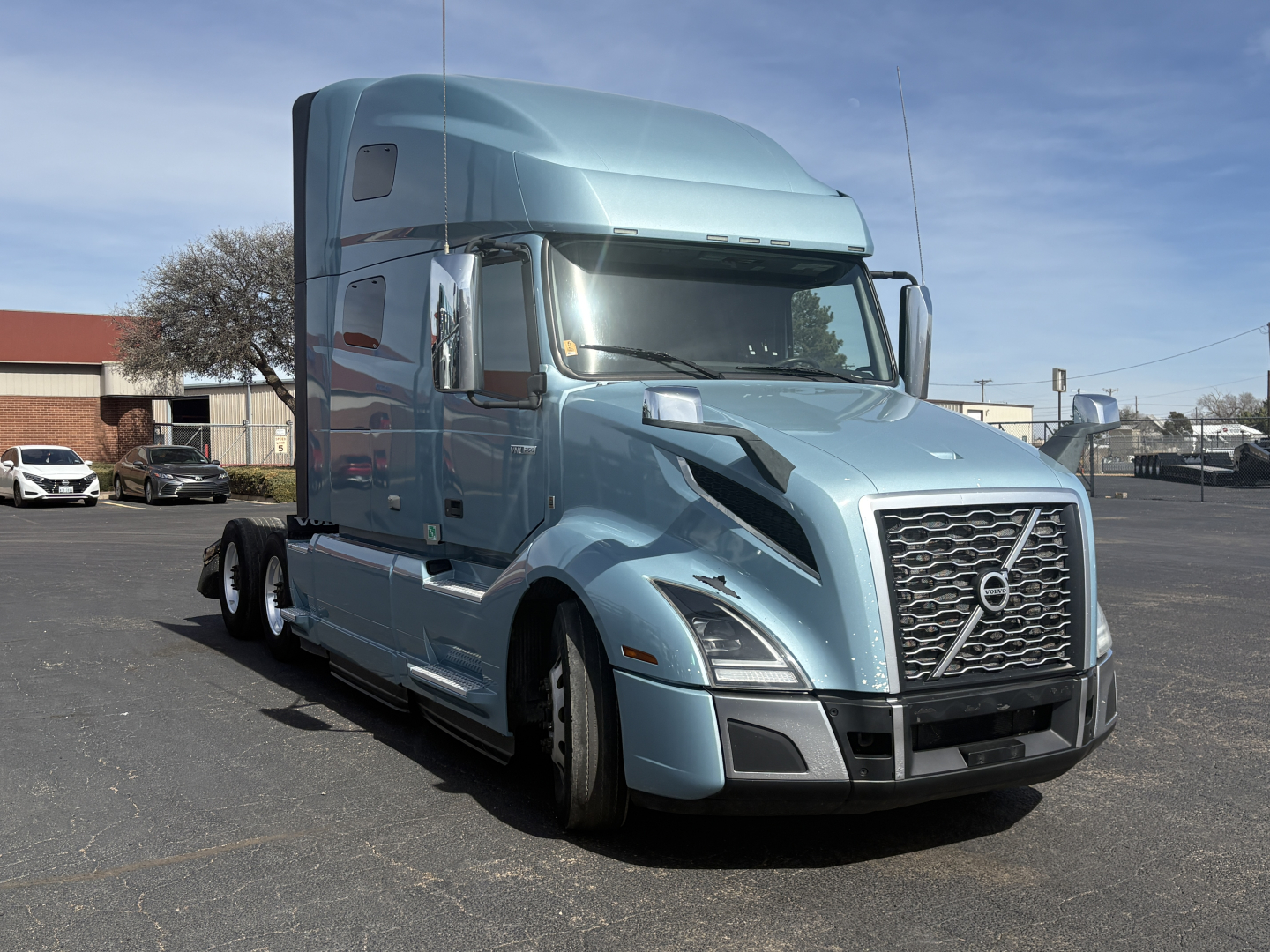 Volvo VNL64T760 semi-truck in blue, side view showing aerodynamic hood and grille, with sleeper cab and dual rear axles.