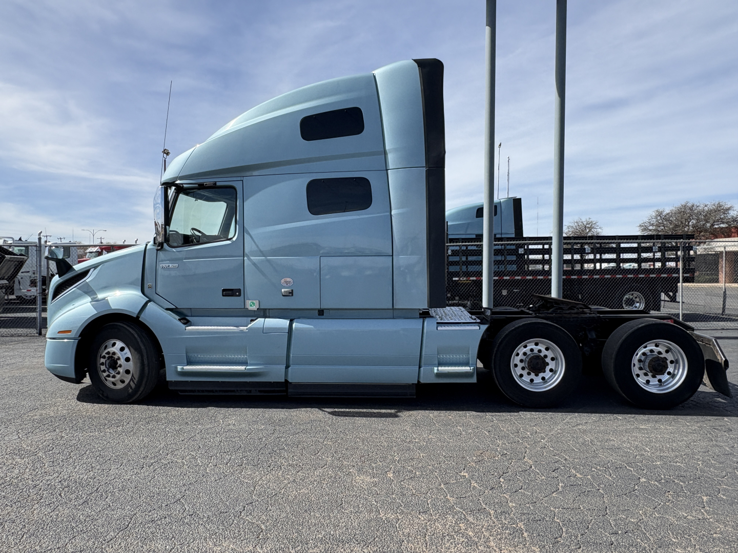 Volvo VNL64T760 conventional sleeper tractor side view showing chrome exhaust, blue exterior, tandem rear axles, and sleeper cab