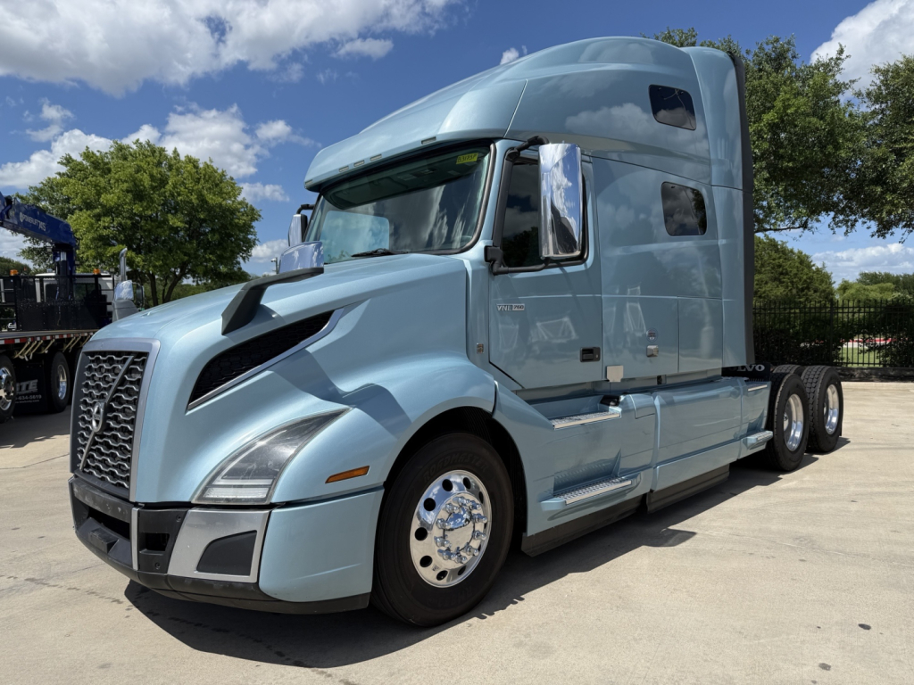 Volvo VNL64T760 truck in blue livery, side view showing sleeper cab and chrome wheels.