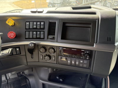 Volvo VNL truck dashboard showing ignition controls, climate dials, radio, and gear selector panel.