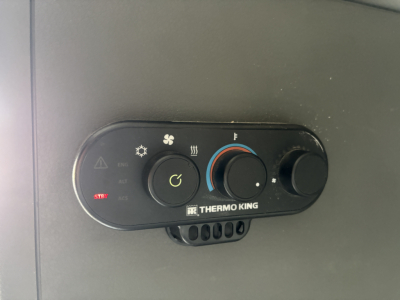 HVAC control panel with Thermo King branding in a Volvo VNL truck showing temperature dial and fan speed settings.