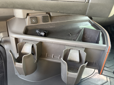 Volvo VNL64T760 truck interior storage area showing cup holders and a small open tray with surrounding compartments.