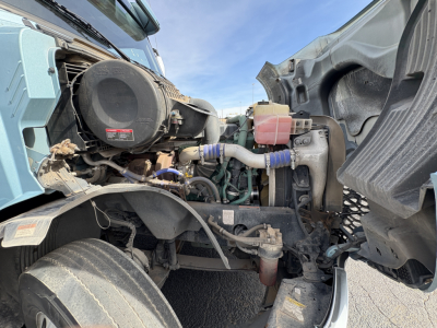 Engine bay of a 2022 Volvo VNL64T760 with visible hoses, reservoir, and intake components in a cab-forward layout.