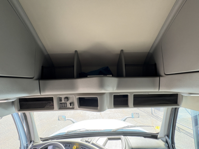 Cab interior overhead with storage compartments and dash area in Volvo VNL64T760 sleeper cab showing overhead compartments and cockpit window view.