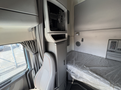 Interior sleeper cab of a 2022 Volvo VNL64T760 showing dashboard panel with empty space for infotainment, window with curtain, and plastic-covered bunk area.