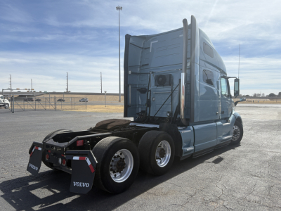 Truck tractor in a parking lot showing rear and side view with sleeper cab, Volvo mud flaps, and fifth wheel area.