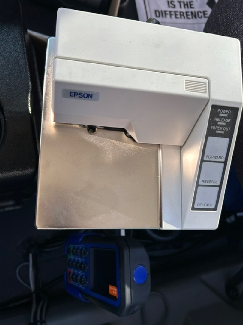Epson printer mounted in truck cabin with control panel on the right and a blue device beneath.