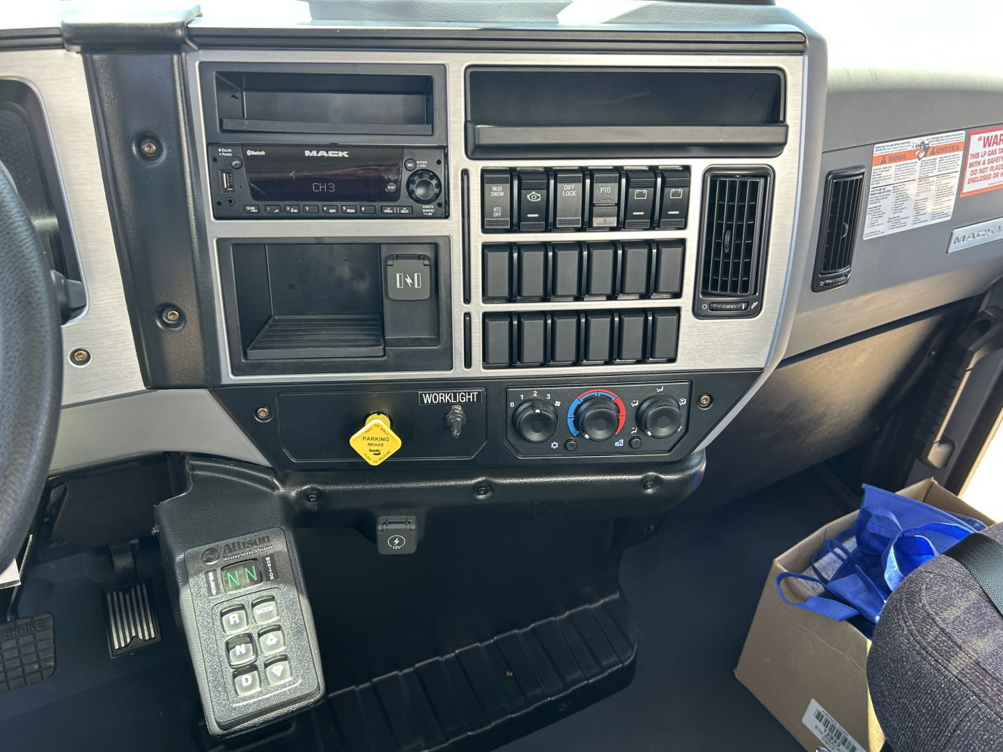 Mack MD7 dash cluster showing radio, climate controls, switches, and ignition area from cab interior.