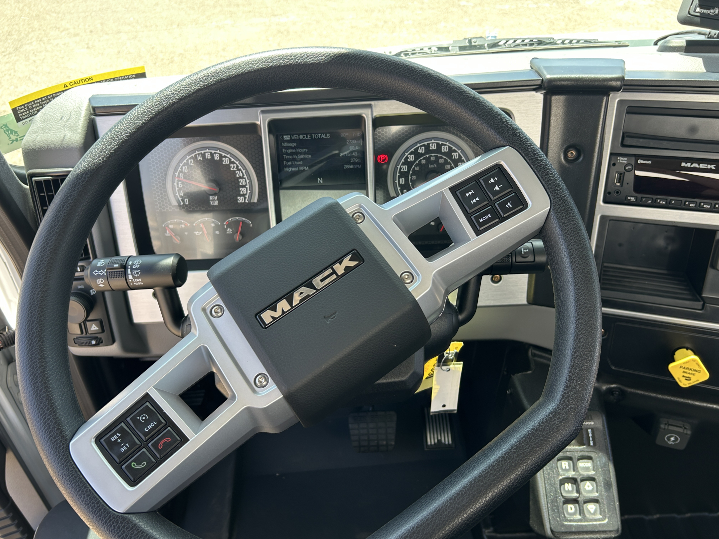 Mack MD7 truck interior steering wheel with dashboard gauges and control stalks visible.