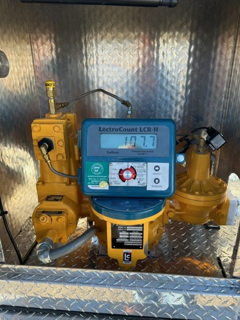 Metered valve assembly with LectroCount flowmeter in blue, yellow hydraulic/pneumatic components, and diamond plate background; visible labels and gauges.