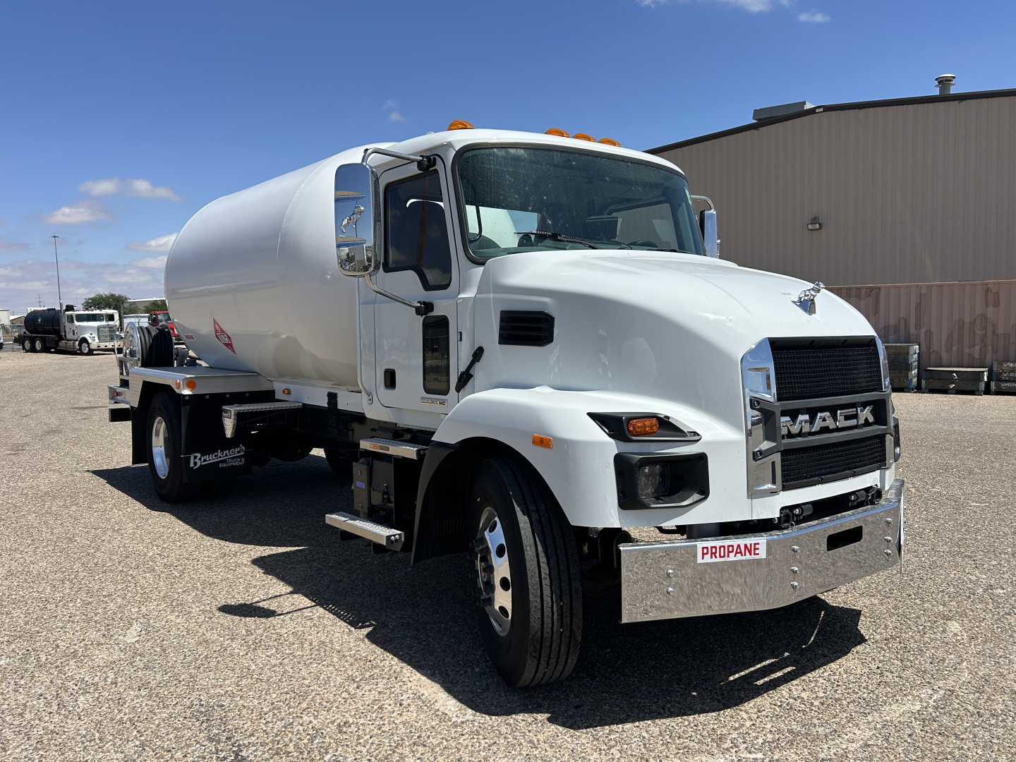Front-left view of a white 2026 Mack MD7 tanker truck showing the cab, chrome grille with MACK emblem, and PROPANE label on the front bumper. Visible text includes MACK on grille and PROPANE on license-plate area; side mirrors and steps are