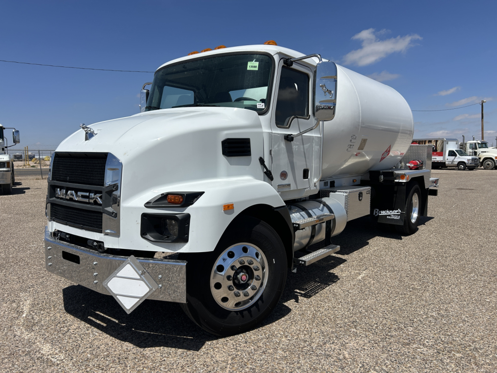 Mack MD7 truck with a white cab and cylindrical tanker mounted on a chassis showing front grille, headlights, and chrome bumper.