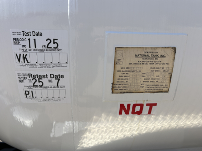 Label plate area on a Mack MD7 truck showing test date stickers and a National Tank, Inc. plate; text includes Test Date, Retest Date, and NOT marking.