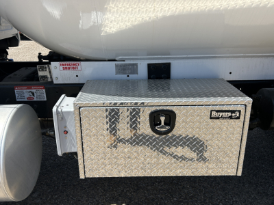 Truck chassis showing diamond-plate aluminum tool chest labeled Buyers, mounted under fuel tank on Mack MD7 cabless truck.