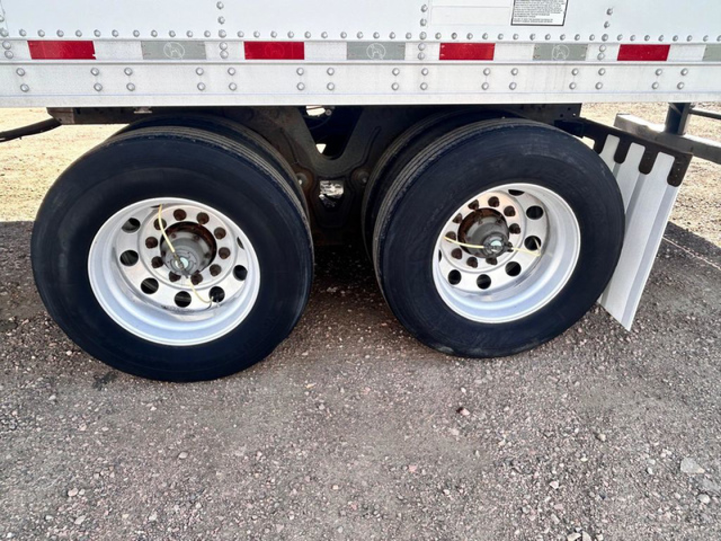Dual rear wheels of a refrigerated trailer with metal rims and black tires under a Great Dane trailer, showing axles and suspension area.