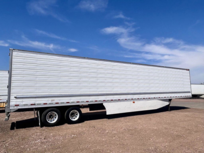 Reefer trailer side view showing tandem axles and aluminum exterior with white side panels.