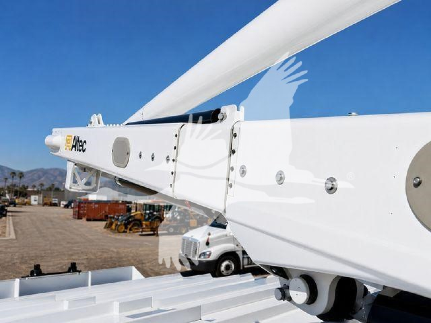 Ford F-750 bucket truck component image showing boom arm and white body with mounting hardware and shop yard in background.