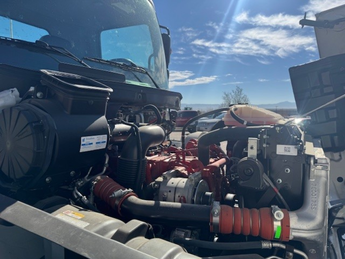 Front engine bay of a 2025 Hino L7 cab and chassis showing engine components, hoses, and label stickers.