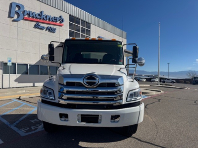 Front view of a white 2025 Hino L7 cab and chassis truck parked outside a dealership with Brackner's sign.