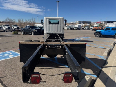 Chassis cab of a 2025 Hino L7 in a dealership lot, rear view showing dual purpose frame rails and taillights.