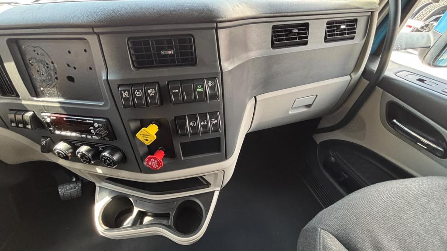 Peterbilt 579 cabin dashboard area showing control switches, knobs, and cup holders.